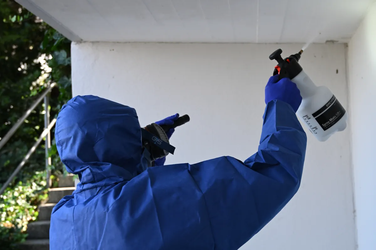 Schädlingsbekämpfer im Schutzanzug im Treppenhaus